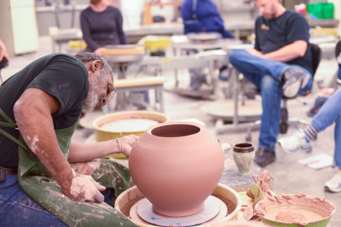 the professor creates a ceramic vase in front of the students.