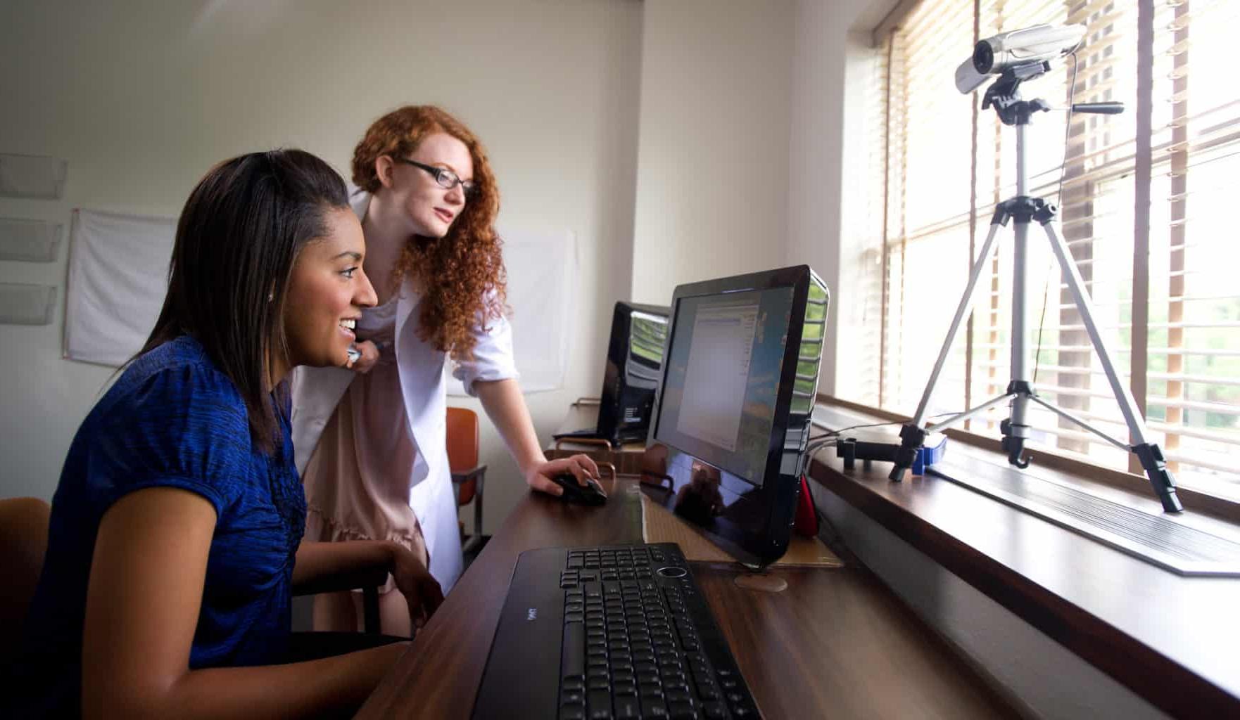 心理学实验室，两个女学生在电脑旁工作.