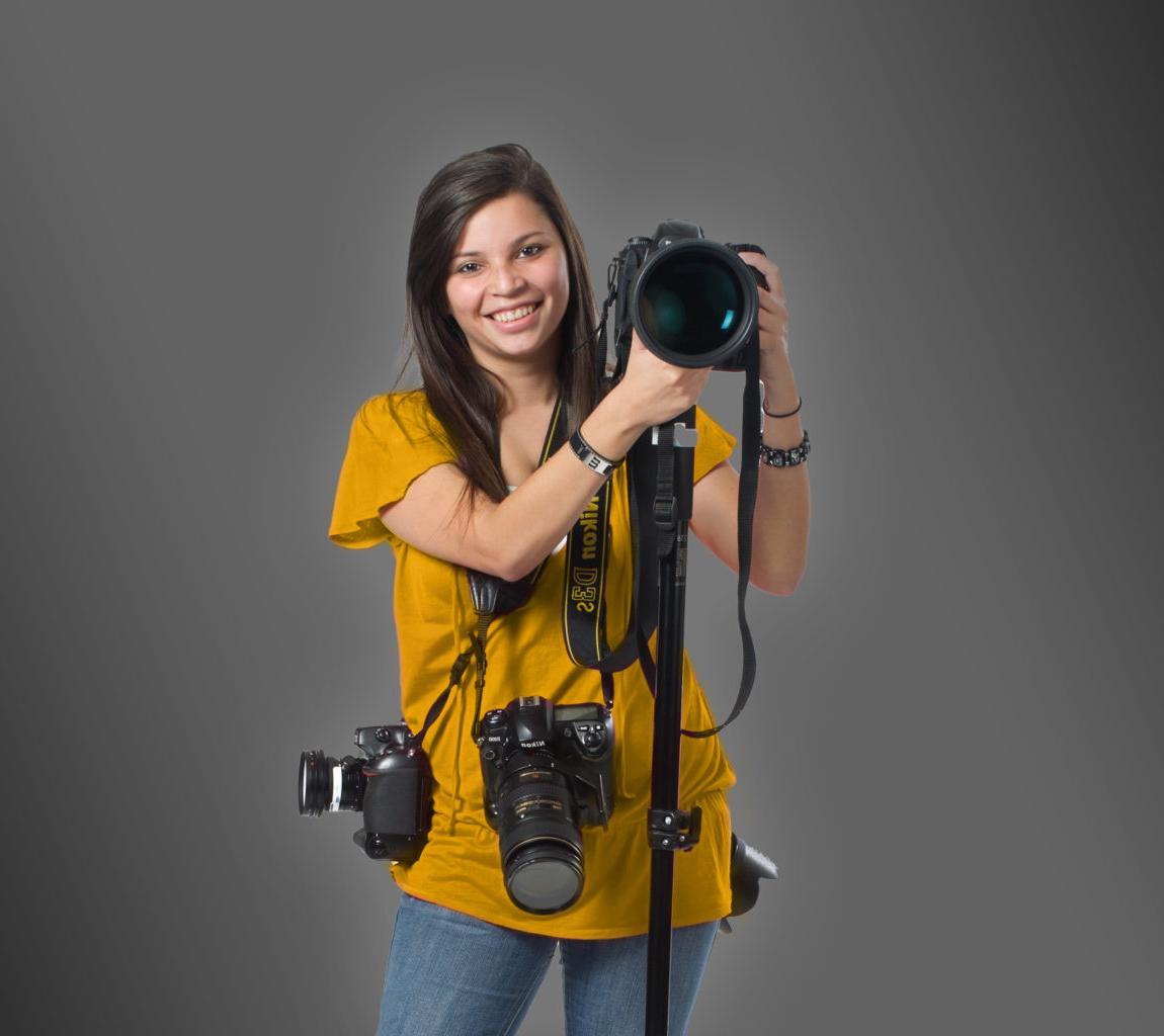 Young woman holding multiple cameras.