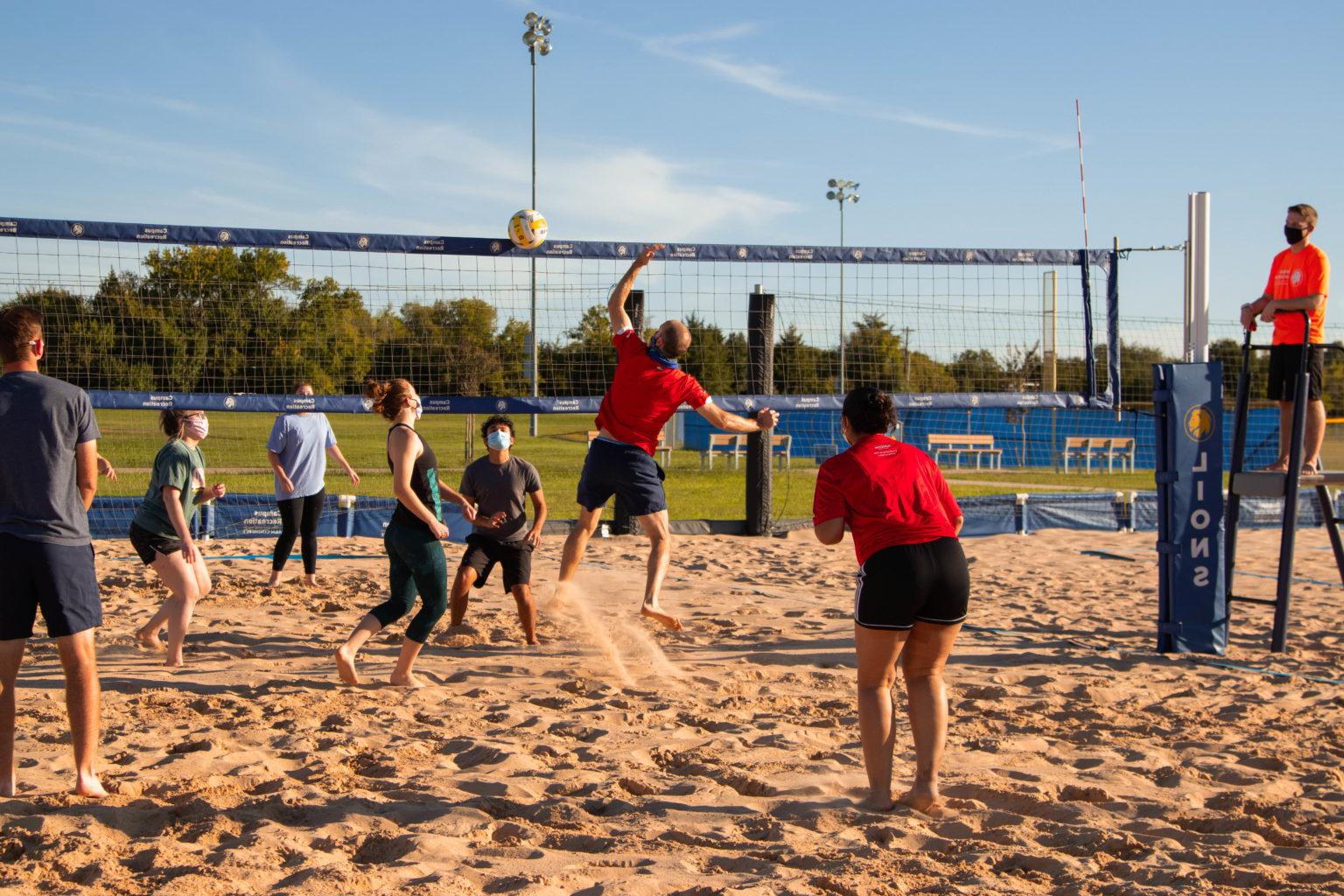A group of people playing sand volleyball at the Cain Sports Complex.